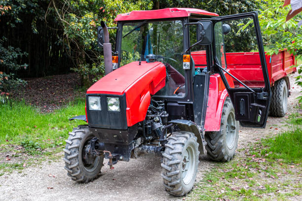 istock Red wheeled tractor with a trailer on a dirt road in a deciduous forest 1398080661