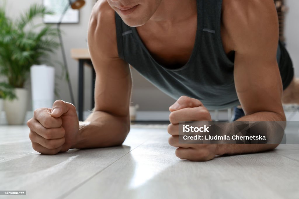 Man doing plank exercise on floor at home, closeup Forearm Stock Photo