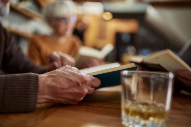 Close up of unrecognizable mature man reading a book at home.