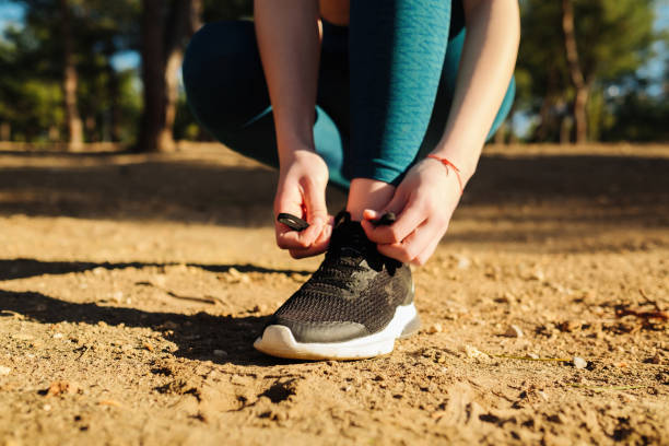 Sportive woman wear running shoe on to walking and running on nature green background. Tying jogging shoes, health exercise and outdoor sport concepts. stock photo