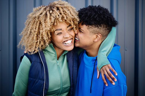 Portrait of a smiling mature woman and her fifteen years old boy, embracing and kissing