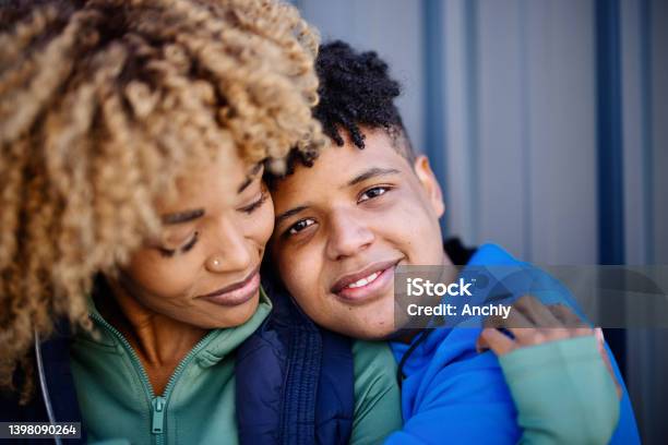 Portrait Of A Teenage Son And Mid Adult Mother Embracing Stock Photo - Download Image Now