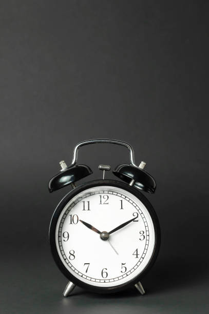 istock Black vintage alarm clock with white dial on black background flat lay copy space. Retro clock, mechanical alarm clock. Minimalistic background, concept of time, deadline, time to work, morning 1398090388