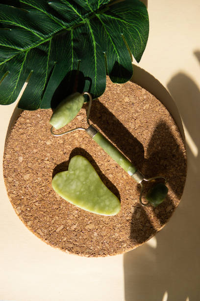 istock Jade Gua sha scraper and face roller massager on a cork round stand with a monstera leaf. 1398090673