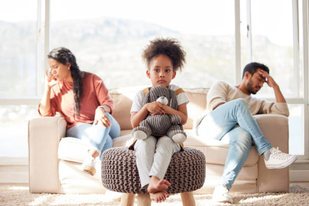 istock Scared little kid with afro sitting and holding teddy bear while parents fight. African American couple ignoring each other after arguing in presence of their daughter. Parents divorce affecting child 1398090703
