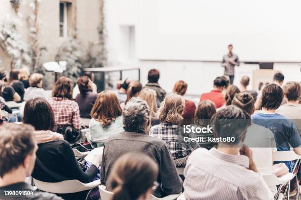 Rear View Of People Sitting In Auditorium Stock Photo - Download Image Now - Conference - Event, Speaker, Auditorium