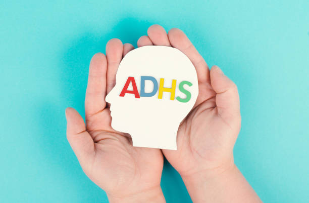 istock Hands holding a head with the german word ADHS which means attention deficit hyperactivity disorder, ADHD symptom, mental health 1398092104
