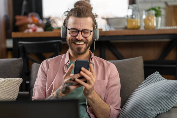 istock Smiling hipster man at home, listening to online classes, or a webinar over a laptop computer 1398093537