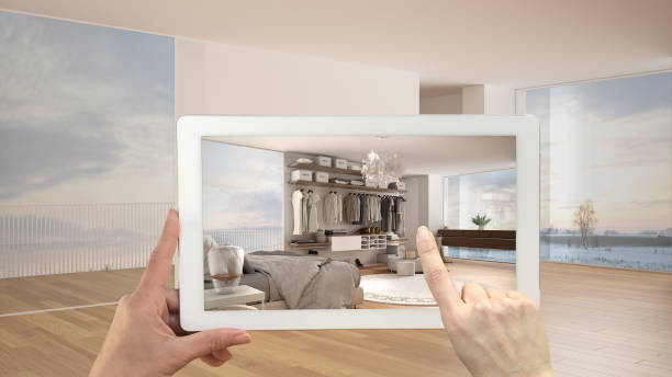 istock Augmented reality concept. Hand holding tablet with AR application used to simulate furniture and design products in empty interior with parquet, luxury bedroom with walk-in closet 1398100330