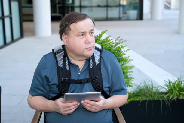 Adult Autistic male sitting along with his digital tablet stock photo