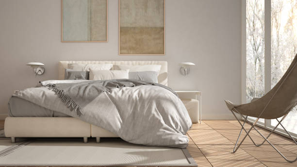 istock Modern white minimalist bedroom, double bed with pillows and blankets, parquet, bedside tables and carpet. Panoramic window with winter panorama with trees and snow, interior design 1398100445
