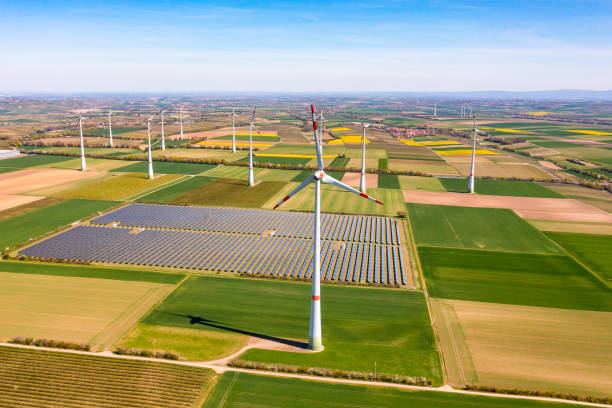 Panorama of solar panels of a solar park amidst wind turbines between agricultural fields stock photo
