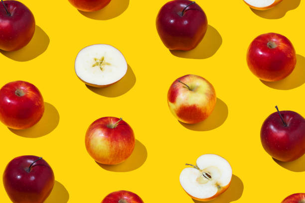 istock Repetitive pattern of whole and sliced apples on yellow background 1398107547