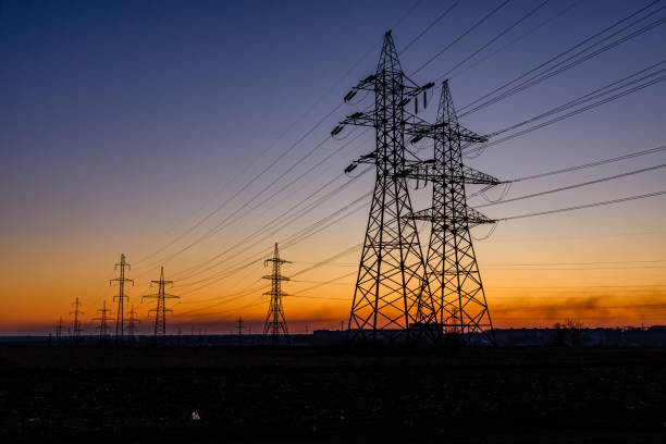 high voltage power line in a field at sunset - torre de transmissão de eletricidade imagens e fotografias de stock