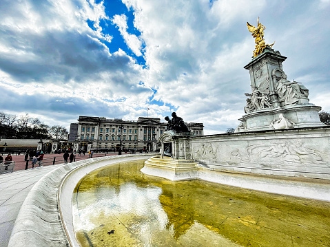London, United Kingdom - March 6 2022: gold plated queen Victoria memorial and fountain with reflection in front of Buckingham Palace