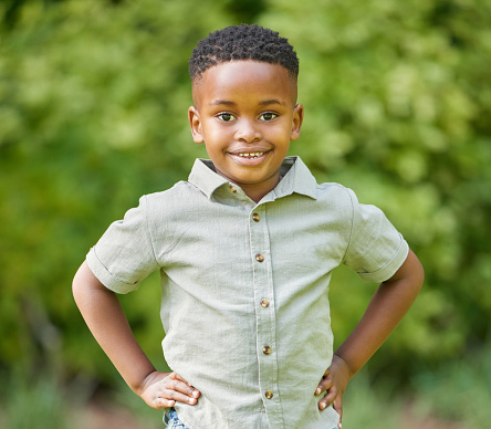 Portrait of a little boy wearing a cyan t-shirt,white pants on blue background.His hands are in his pockets.He is standing on the right side of frame.Copy space on the left side.Shot in studio with medium format camera Hasselblad.