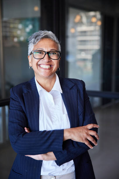 Smiling mature businesswoman standing in the hallway of an office stock photo