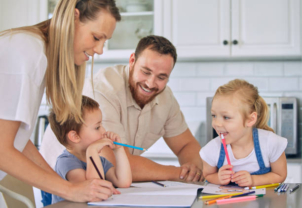 istock Caucasian parents helping children with homework. Happy siblings doing school work. Mother helping her son with homework.Brother and sister drawing with parents. Family doing homework in the kitchen 1398113521