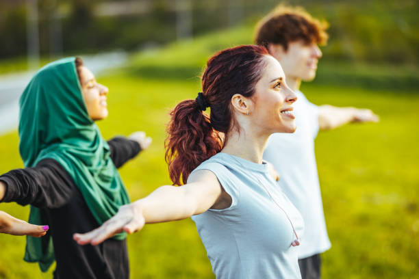 istock Group of people practicing yoga in park 1398114336