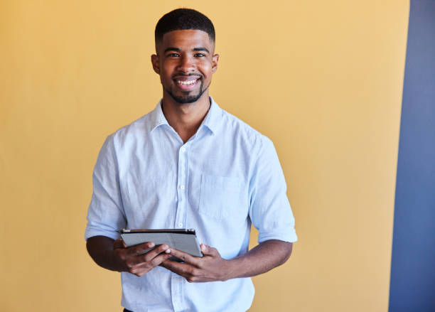 istock Smiling young businessman using a tablet against a yellow background 1398114533