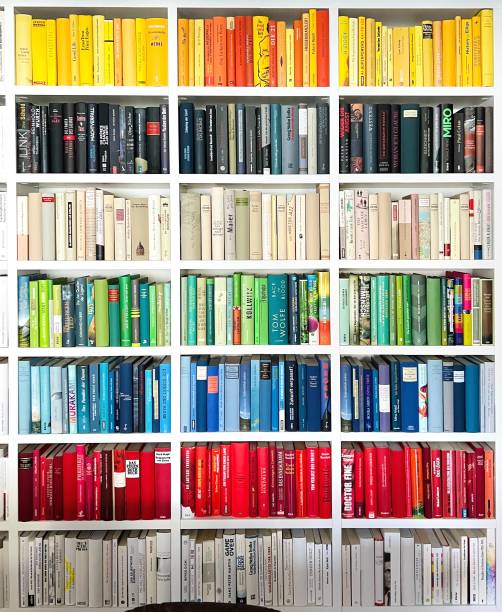 perpustakaan pelangi dengan seri tulang belakang buku kuning, hitam, hijau, biru, merah dan putih - bookshelf potret stok, foto, & gambar bebas royalti