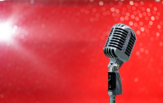 Retro microphone on shiny red background.