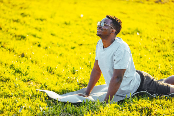 istock Young man in cobra yoga pose on exercise mat doing stretching exercise in nature. 1398116003