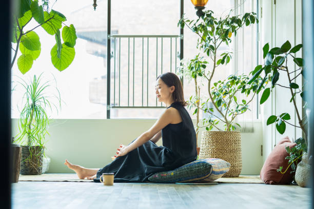 A woman relaxing surrounded by foliage plants A woman relaxing surrounded by foliage plants in the room simple living photos stock pictures, royalty-free photos & images
