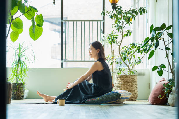 A woman relaxing surrounded by foliage plants A woman relaxing surrounded by foliage plants in the room japanese ethnicity stock pictures, royalty-free photos & images