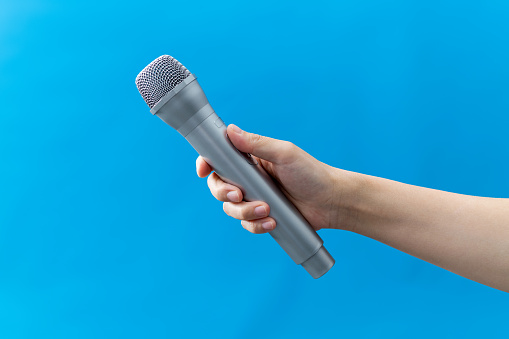 Hand holding a wireless microphone on white background.