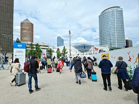 Outside the Lyon-Part-Dieu station with several people just left the Station building. Lyon-Part-Dieu station was opened in 1983. The image was captured during springtime, in the background visible several tall building as part of part-dieu city district.