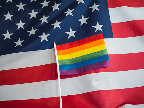 United States flag with flag of the LGBT community together for pride day on June 28. Freedom and equality concept