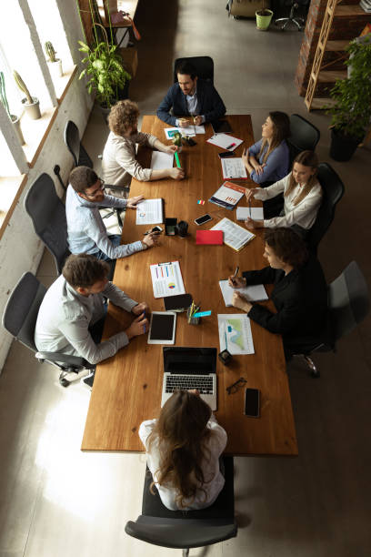 Aerial view of young people, co-workers during work process, meeting at office, indoors. Work, finance, tech and business concept.