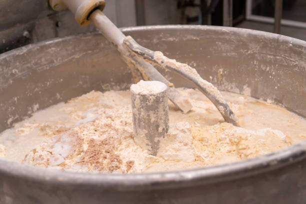 Close-up of the process of kneading mixing bread dough in a kneading machine in a bakery. Industrial mixer for kneading dough. One of the stages of making bread dough Close-up of the process of kneading mixing bread dough in a kneading machine in a bakery. Industrial mixer for kneading dough. One of the stages of making bread dough mixing vat stock pictures, royalty-free photos & images