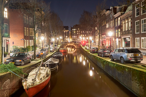 Amsterdam city street with narrow canal at night, The Netherlands