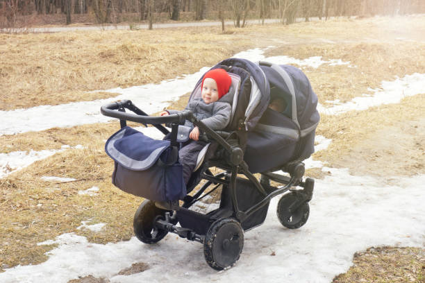 istock Two small children in double stroller. Sun, early spring, melting snow, last year's grass 1398125573