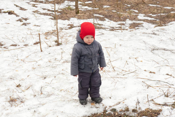 istock Small child in red cap and gray clothes standing up in spring forest 1398126371