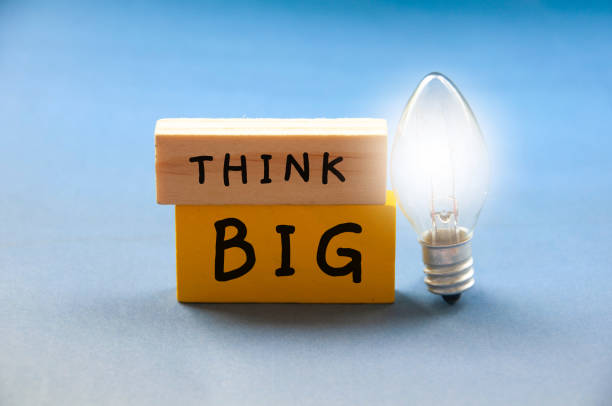 istock Think big text on wooden blocks with shining bulb on light blue background. Motivational 1398126859
