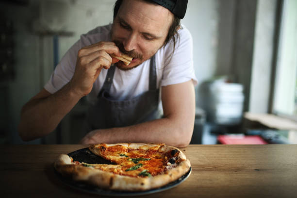 Pizza chef eating a freshly baked pizza. stock photo