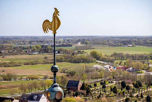 A weather vane with a flying eagle on a cupola with a blue and cloudy sky for a background.