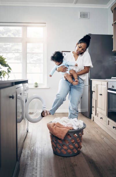 istock Shot of a young mother using a cellphone while completing housework and holding her baby at home 1398131330