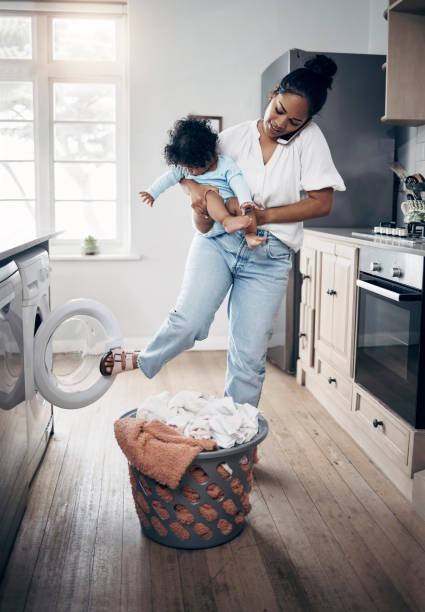 istock Shot of a young mother using a cellphone while completing housework and holding her baby at home 1398131331