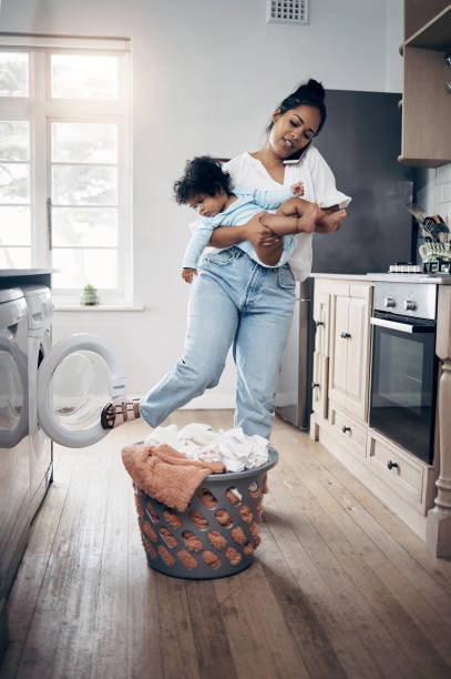 istock Shot of a young mother using a cellphone while completing housework and holding her baby at home 1398131336