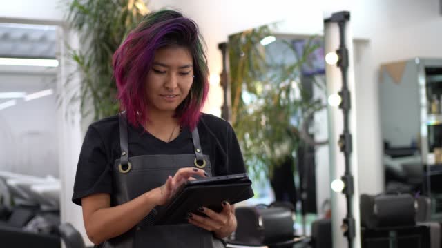 Hairdresser using digital tablet at hair salon