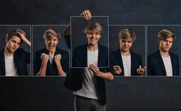 Photo of young man holding face portraits with different emotions