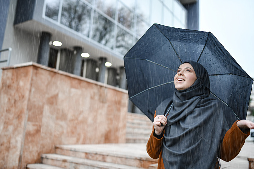 Cute Muslim Female With Hijab Battling Rain With Umbrella While Taking Walk