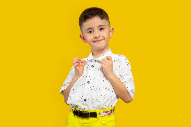 Portrait of a cute little boy posing against a yellow background and confident stock photo
