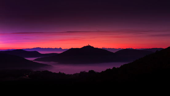 Dusk Panorama of Landscape of Mountains and Valleys covered under mist - Town Grgar with Mount Sveta Gora and Dolomites in the background - Slovenia.