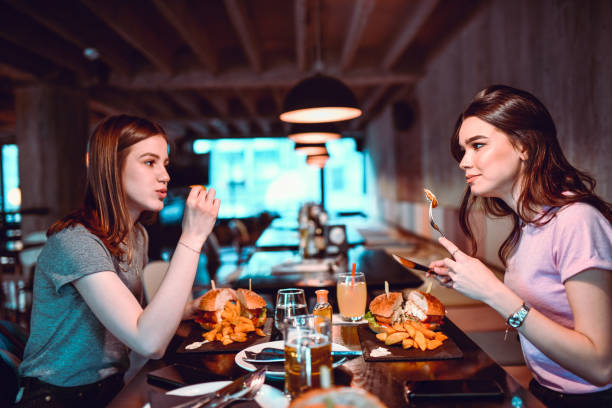 istock Beautiful Females Eating Burger Dinner Together 1398140084