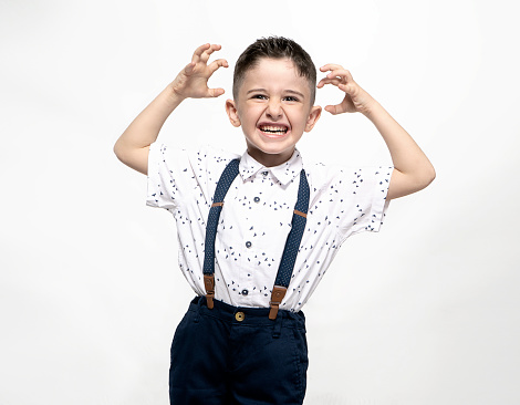 Funny Caucasian preschooler child girl dressed cook chef baker in apron and hat with plastic fork and knife fooling around, making faces on chroma key background. Cooking school, children education